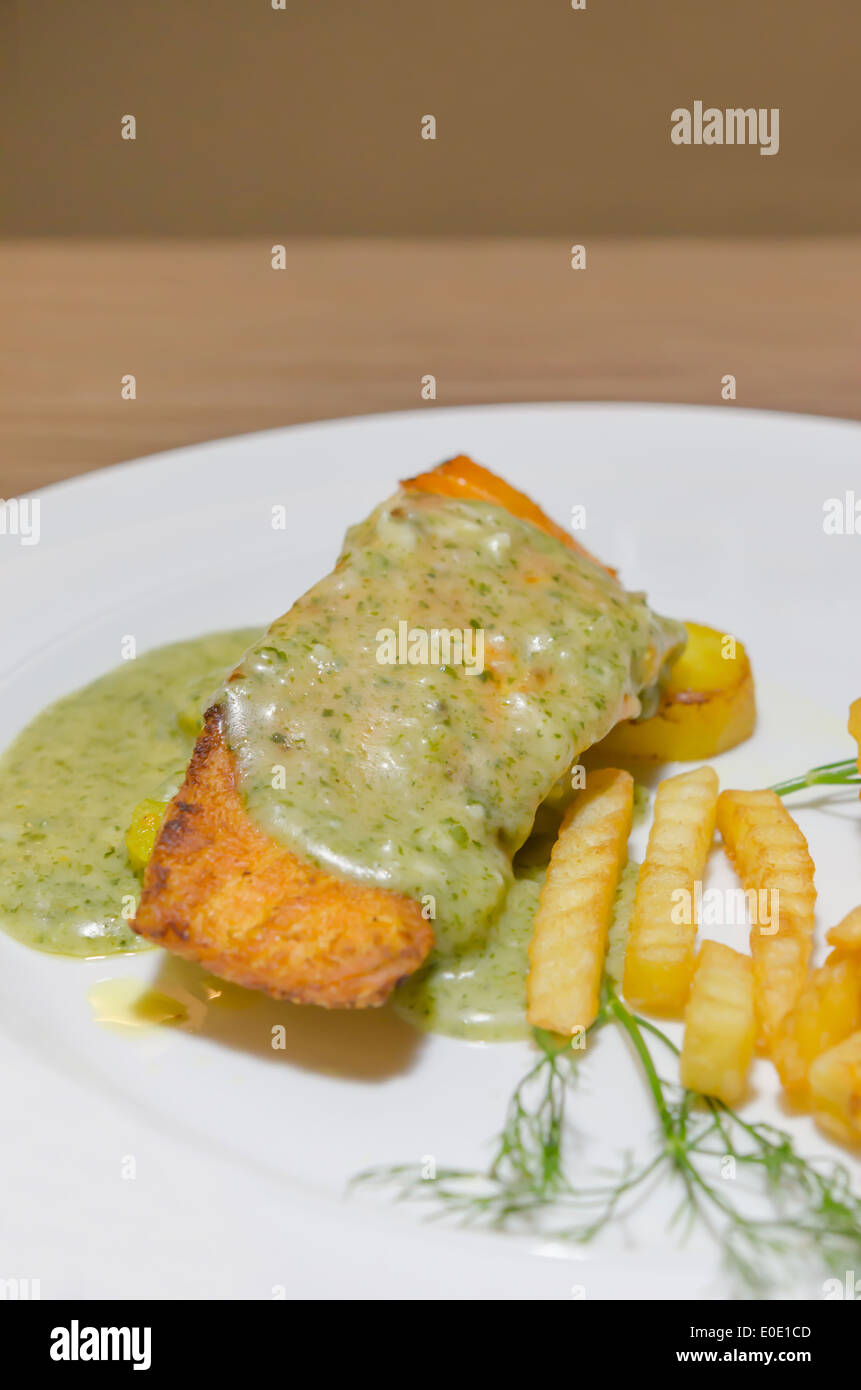 roasted salmon served with green sauce and french fries on white plate Stock Photo
