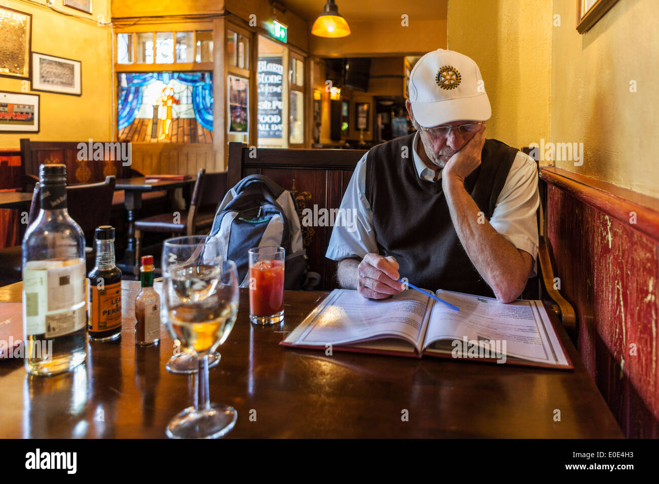 Senior man reading menu in interior of a typical Irish themed pub - the 'Blarney Stone' in Windsor, England Stock Photo