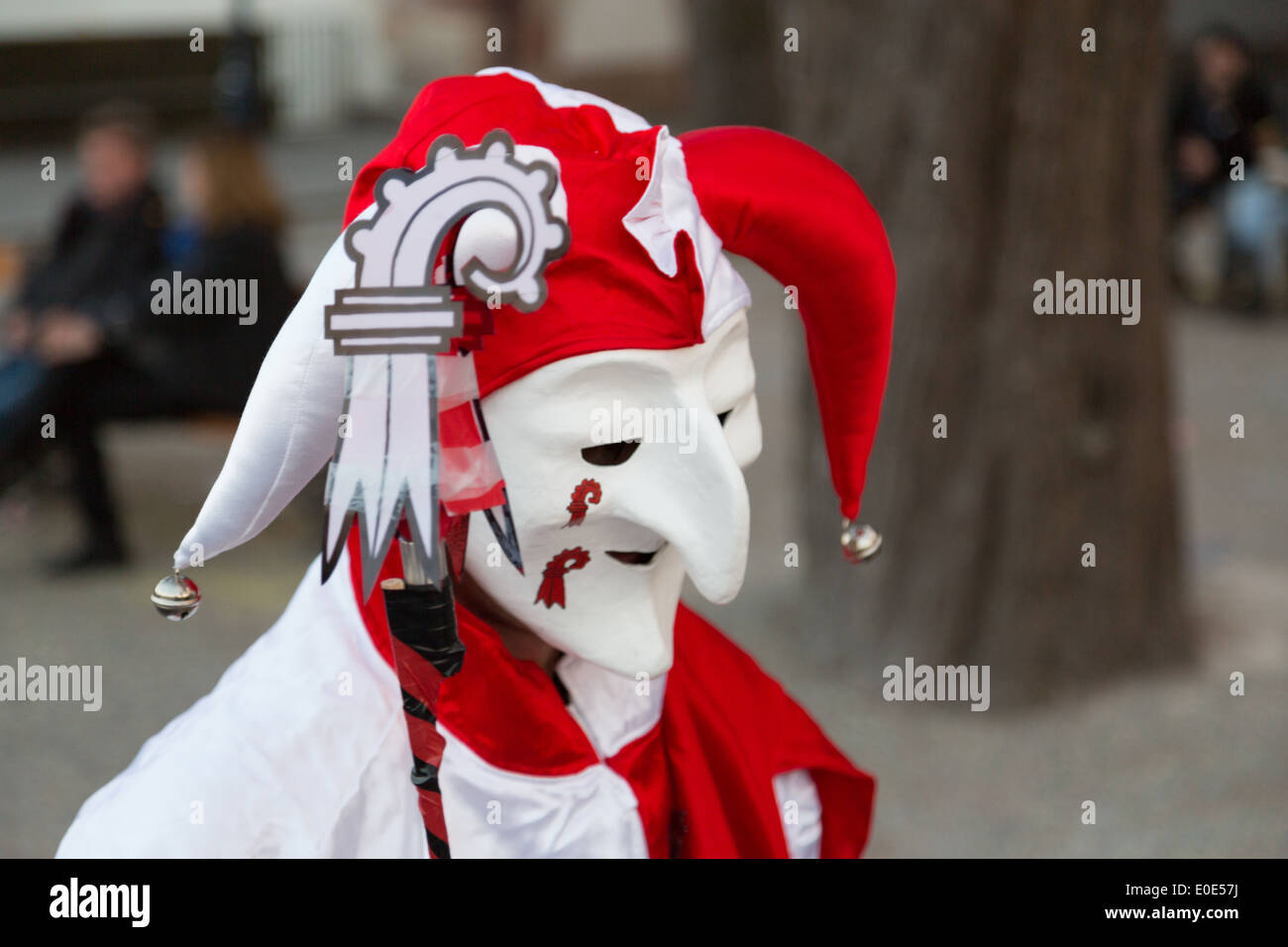 A photograph of a parade participant dressed as a red and white jester at a carnival in Europe. Stock Photo