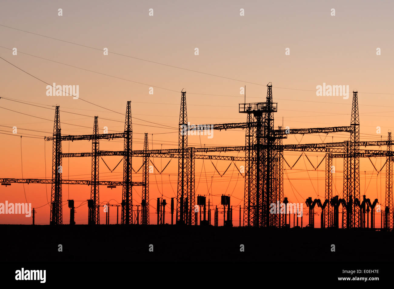 Silhouetted power pylons against a red sky at sunset Stock Photo