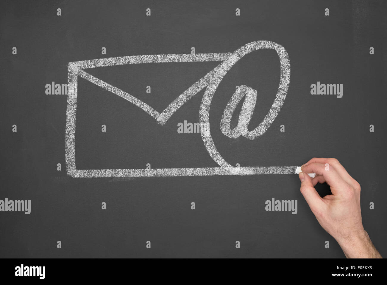 A businessman drawing an email symbol on a chalkboard. Stock Photo