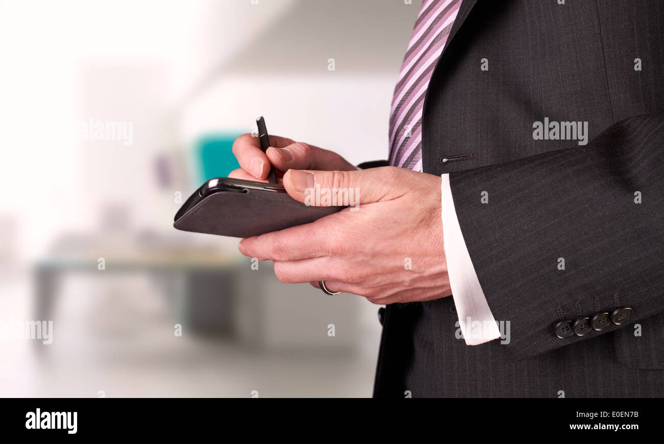 A businessman writing a message with a stylus on an electronic device. Stock Photo