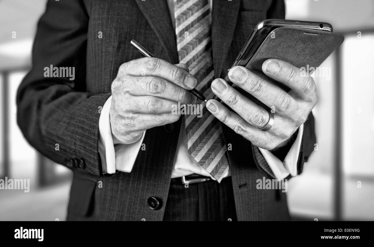 A businessman writing a message with a stylus on an electronic device. Stock Photo