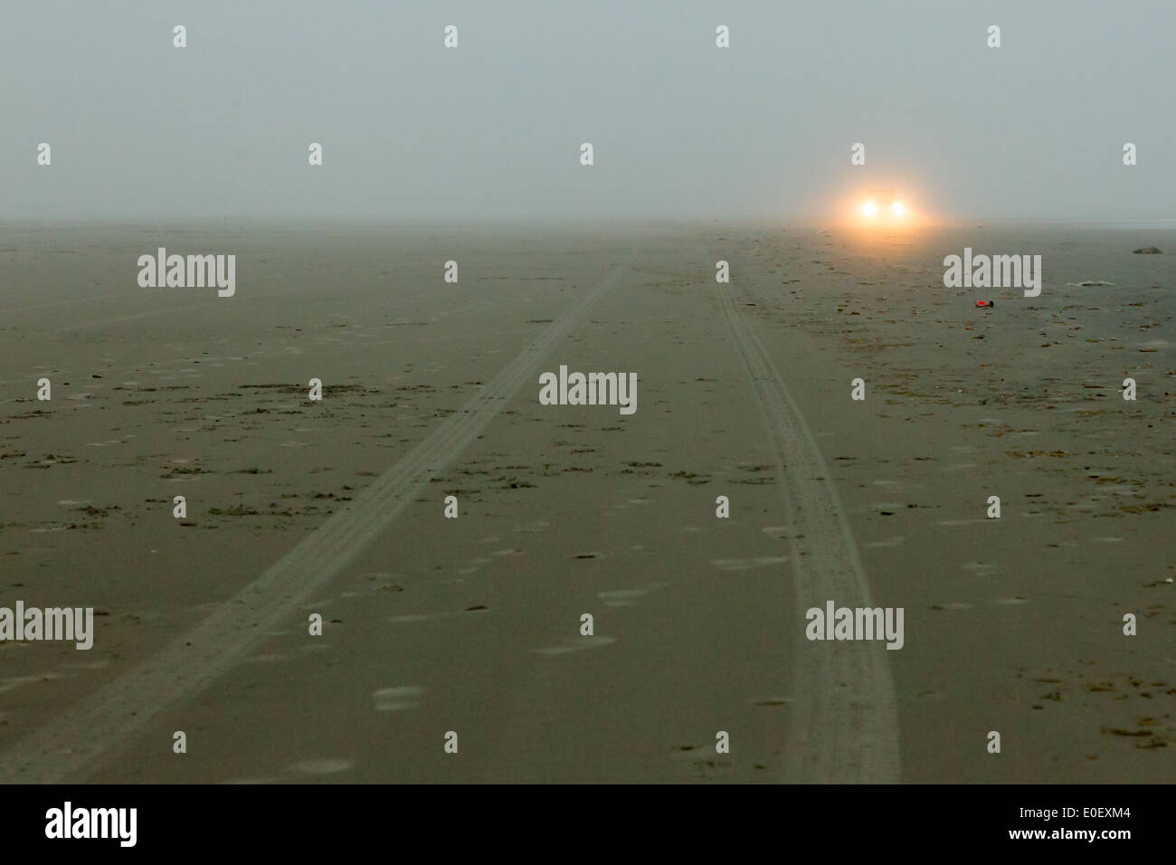 Car headlights of a car on the beach, mist Stock Photo