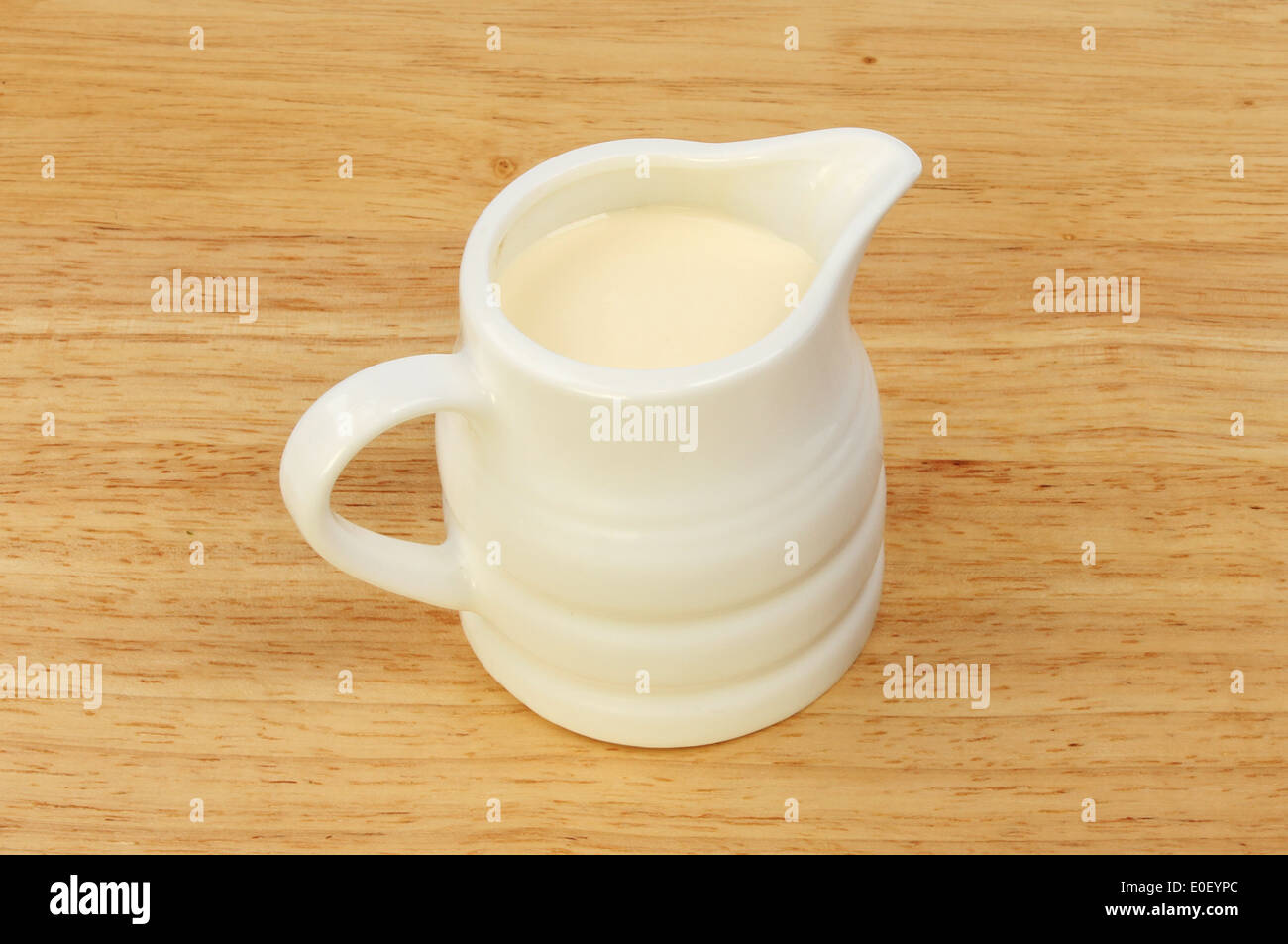 Jug of cream on a wooden board Stock Photo