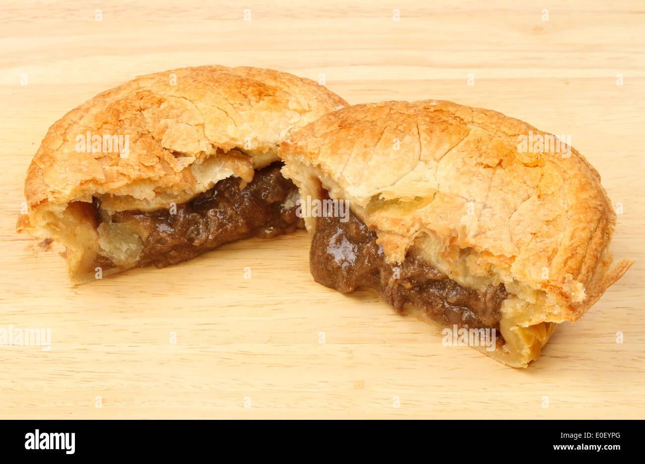 Cooked meat pie cut in half on a wooden board Stock Photo