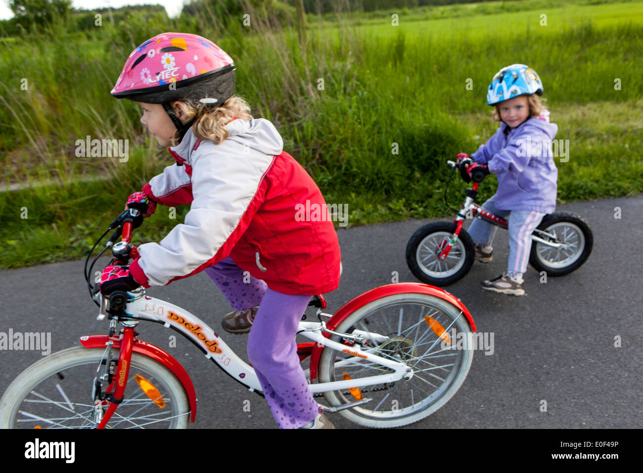 Two toddlers with bike helmets Children riding bikes Cycling on cycle path Children ride bike Stock Photo