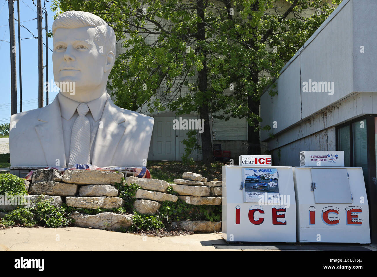 A giant statue of the head of president John F. Kennedy next to a gas