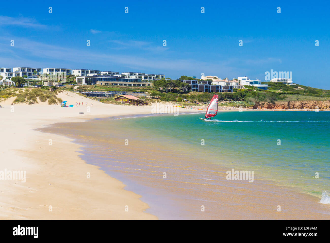 Windsurfer on Martinhal beach with martinhal beach resort hotel on the cliffs behind Sagres Algarve Portugal EU Europe Stock Photo