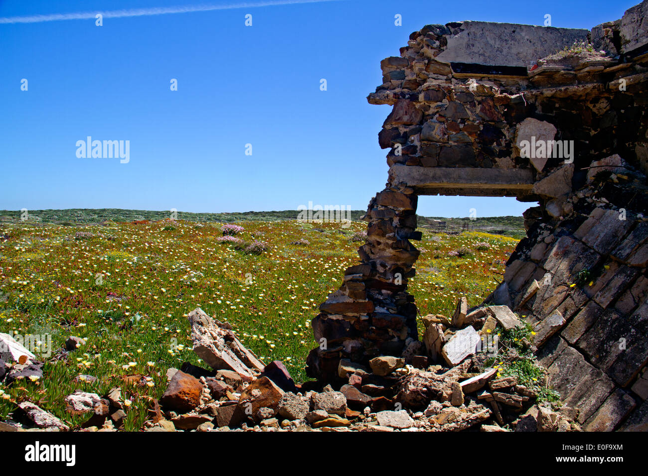 Ruin of a building in a meadow with flowers near Pedra da Atalaia in the Algarve, Portugal Stock Photo