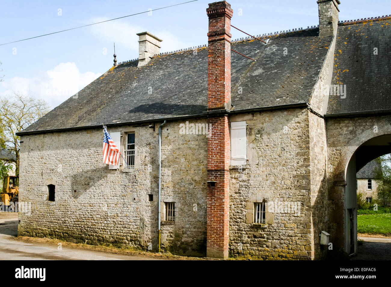 American flag hangng from window of old farm house in Sainte-Marie-du-Mont, Normandy, France. Stock Photo