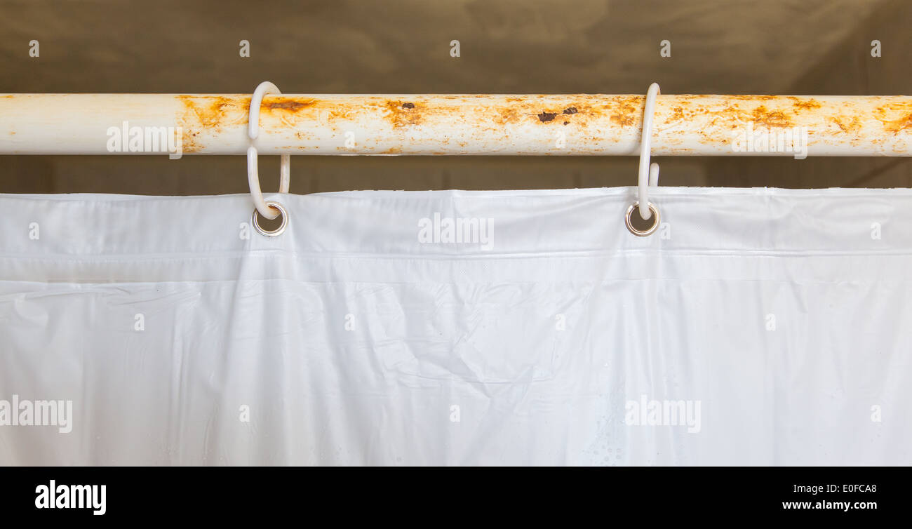 White shower curtain in the bathroom, hanging on a rusted bar Stock
