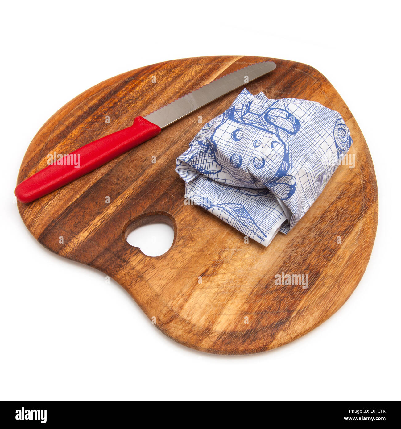 Heart shaped cheese board with a knife and wrapped cheese isolated on a white studio background. Stock Photo