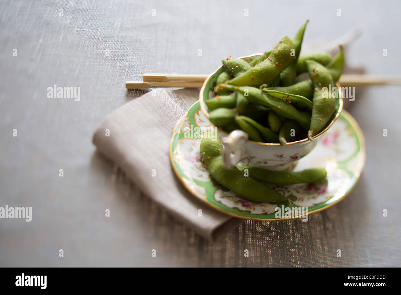 Tea cup of chilli edamame with chop sticks Stock Photo