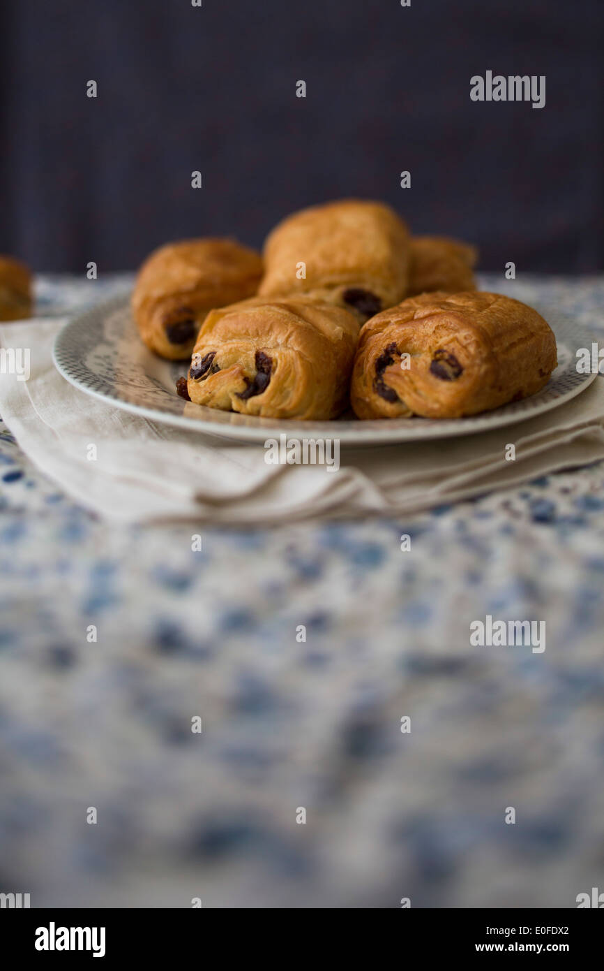 Plate of Pain Au Chocolat on a blue floral table cloth and dark blue background Stock Photo