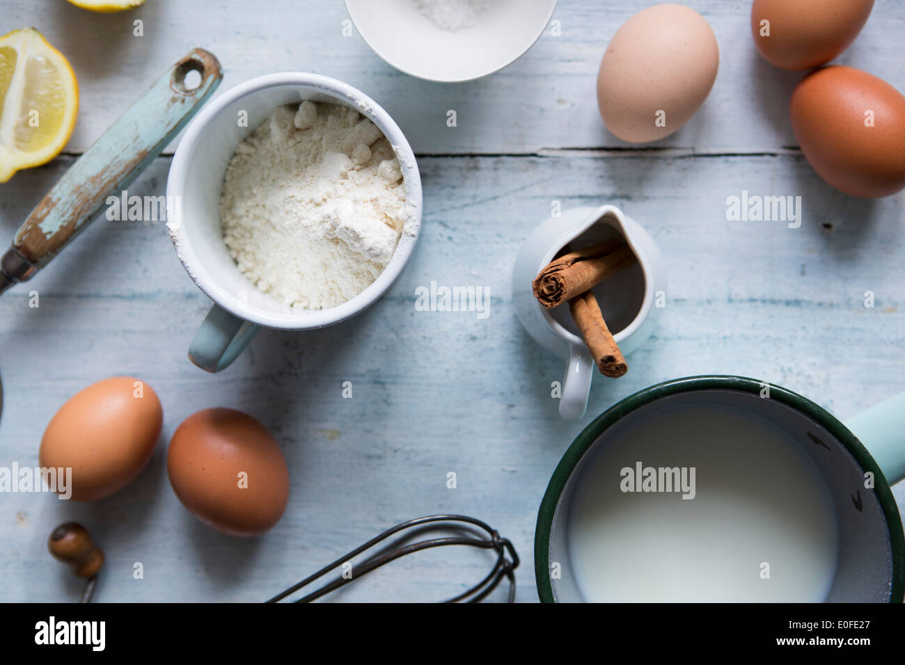 Ingredients for making pancakes, including eggs, flour cinnamon and a whisk Stock Photo