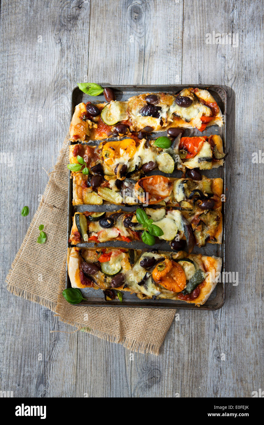 Homemade Roasted Vegetable Pizza with Olives, Basil and Peppers, Sliced Stock Photo