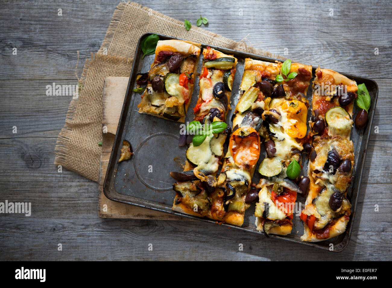 Homemade Roasted Vegetable Pizza with Olives, Basil and Peppers, Sliced Stock Photo