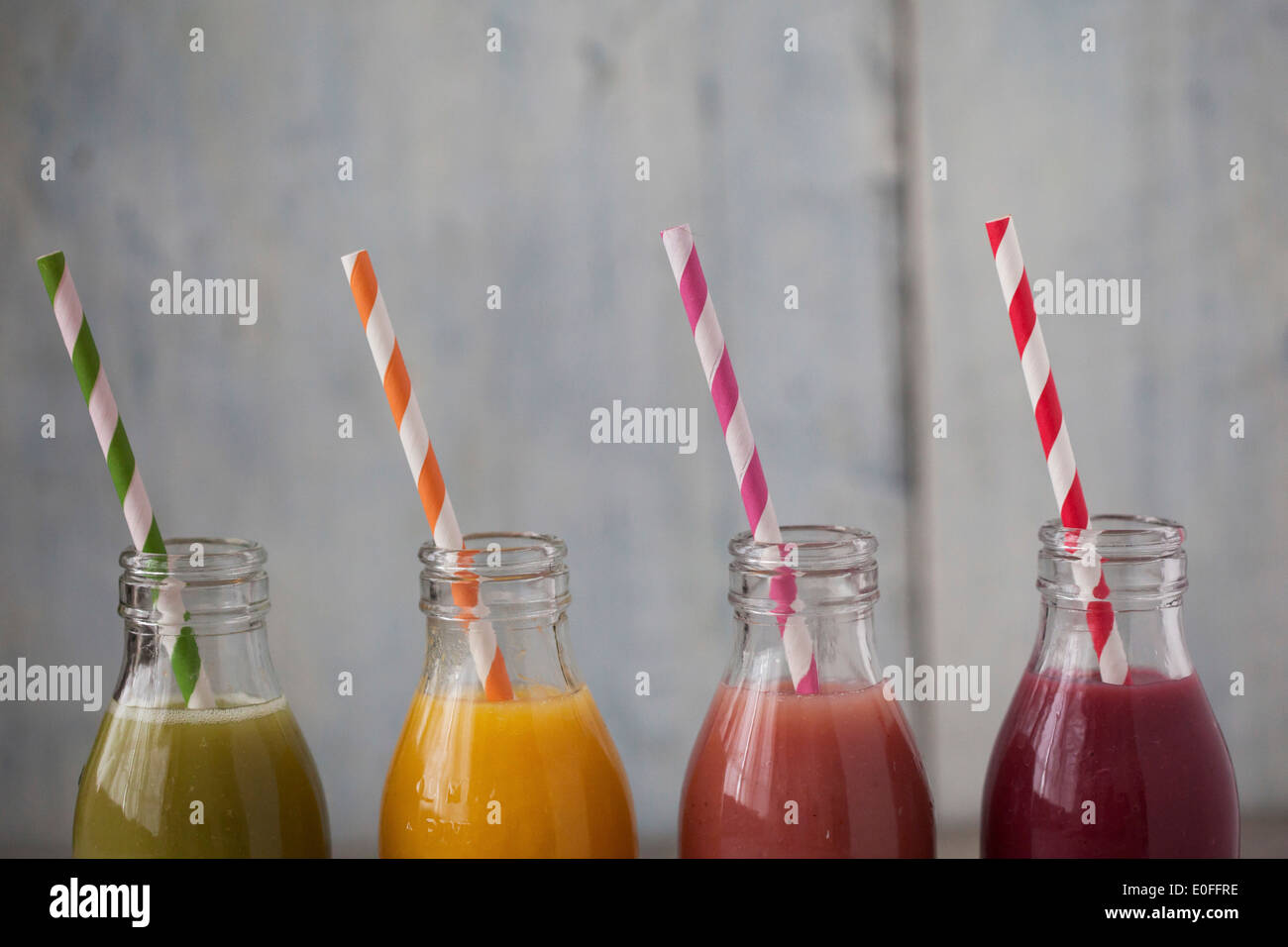 Four different smoothie flavours in mini milk bottles with straws Stock Photo