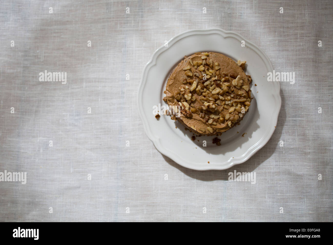 Top View Walnut and Coffee Cake on a white plate and white table cloth Stock Photo