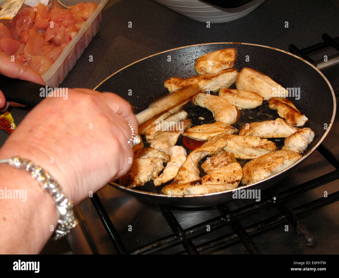 Woman frying chicken pieces in pan Stock Photo