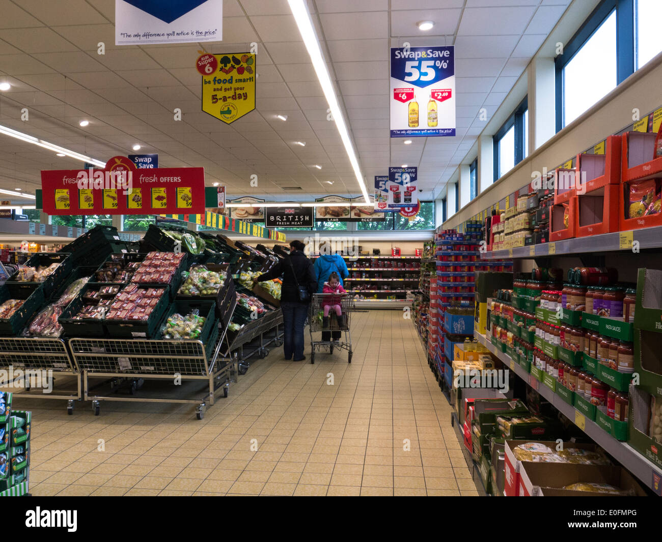 Two female shoppers with little girl in shopping trolley in Aldi