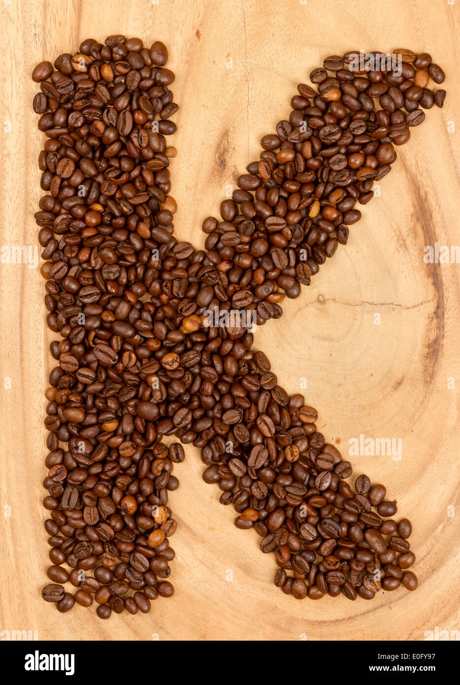 Letter K, alphabet from coffee beans. isolated on wood Stock Photo