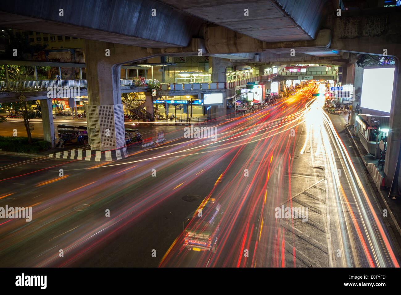 Light trails of vehicles at a street under a concrete bridge at night ...