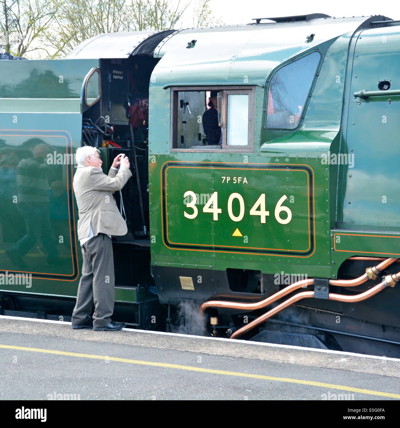 Man with camera taking close up photo of footplate of preserved steam engine 34046 Braunton during stop Banbury train station Oxfordshire England UK Stock Photo