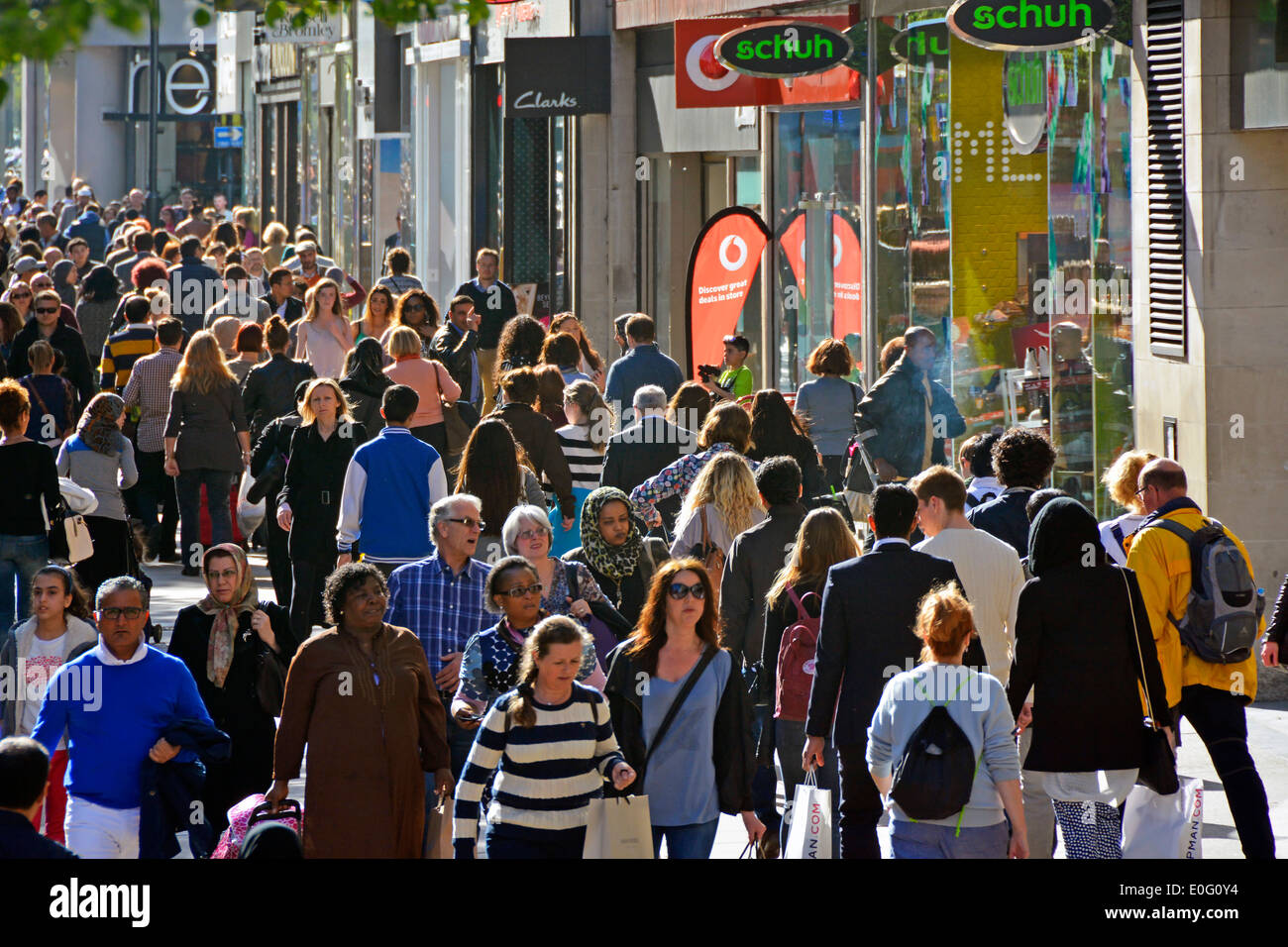 Looking down from above at famous busy shoppers Oxford Street shop fronts with crowd of backlit shopping people walking in West End London England UK Stock Photo