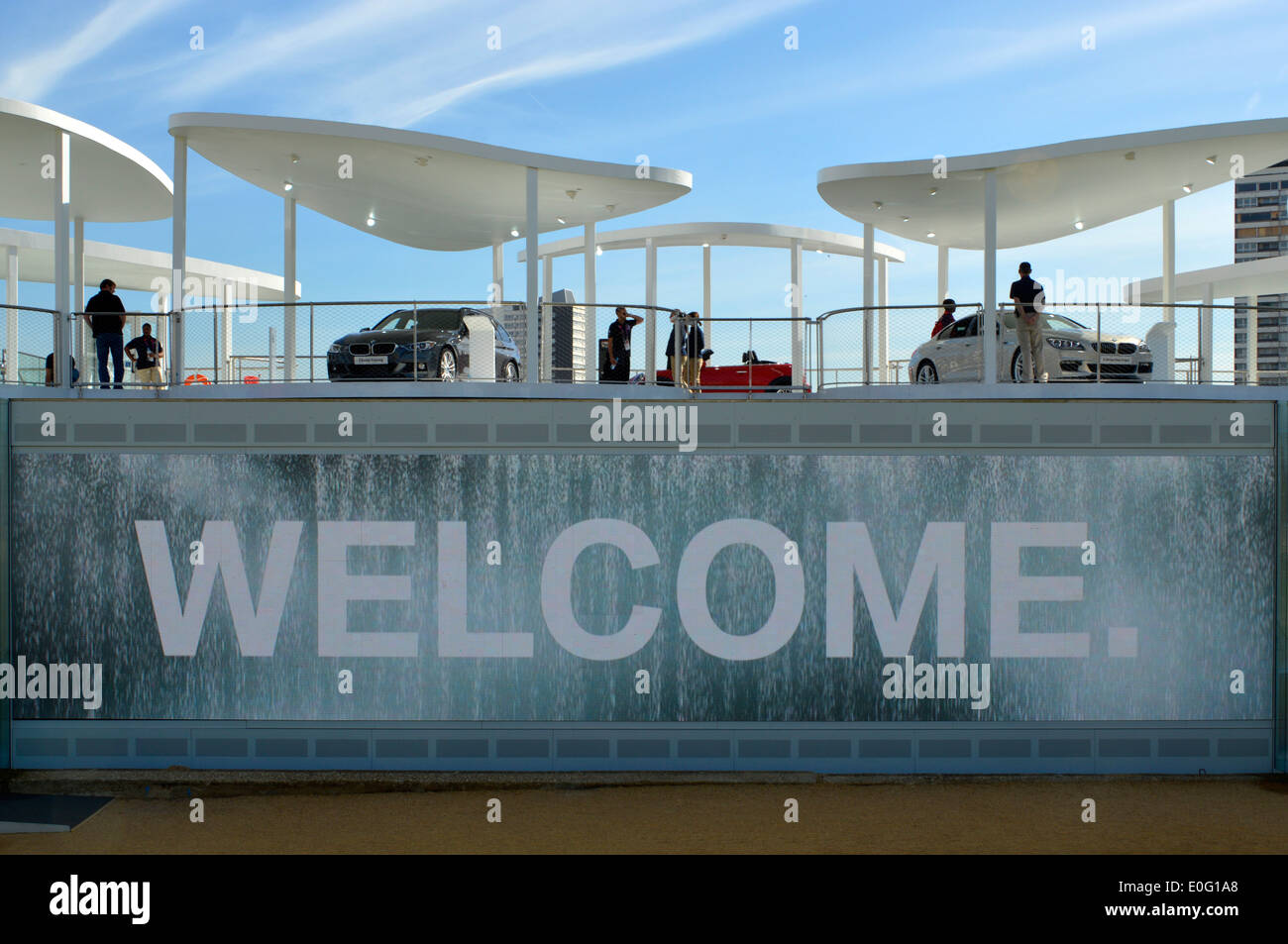 BMW outdoor car showroom in the London 2012 Olympic Park above large TV panel showing welcome sign behind falling water Stock Photo