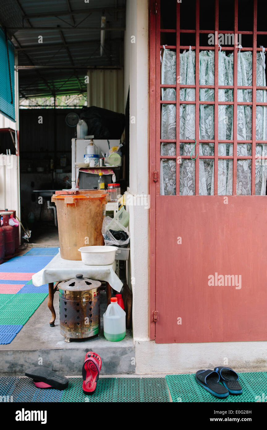 Backyard of a home in Penang, Malaysia with sandals at the doorstep and miscellaneous items along the wall. Stock Photo