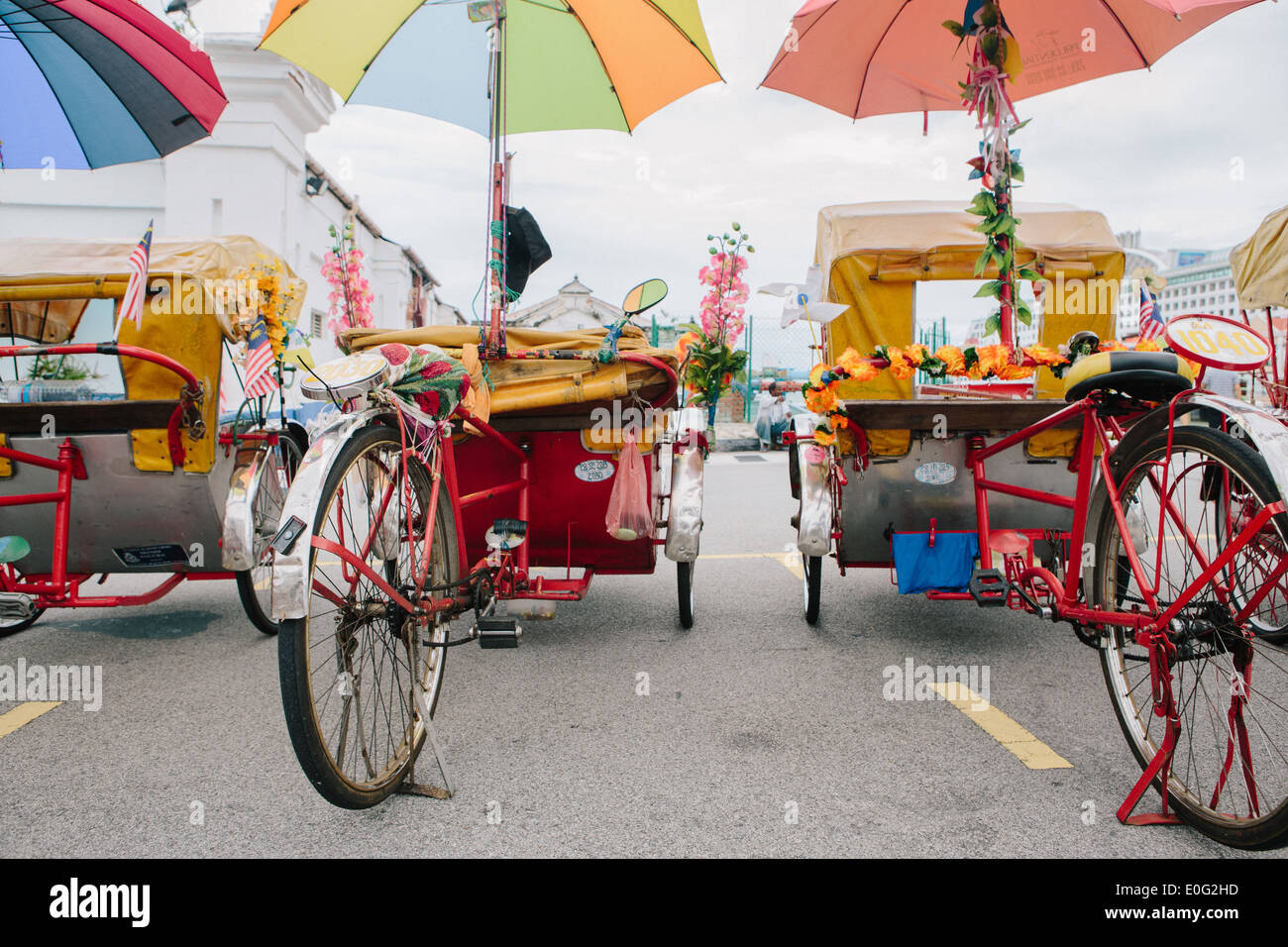 Behind two trishaws with colorful umbrellas looking out. Stock Photo