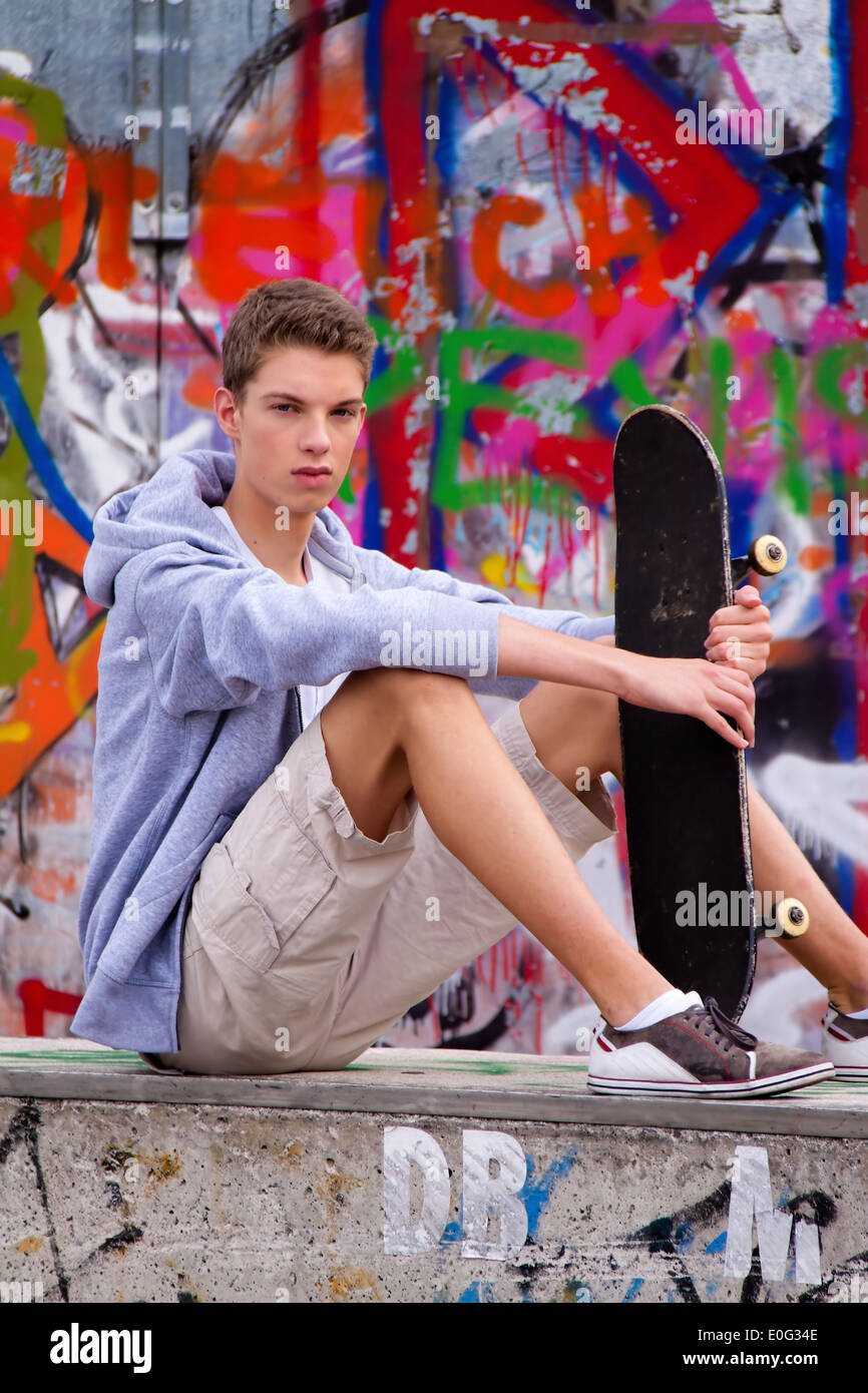 A cool looking youthful man before graffiti, Ein cool blickender Jugendlicher Mann vor Graffiti Stock Photo