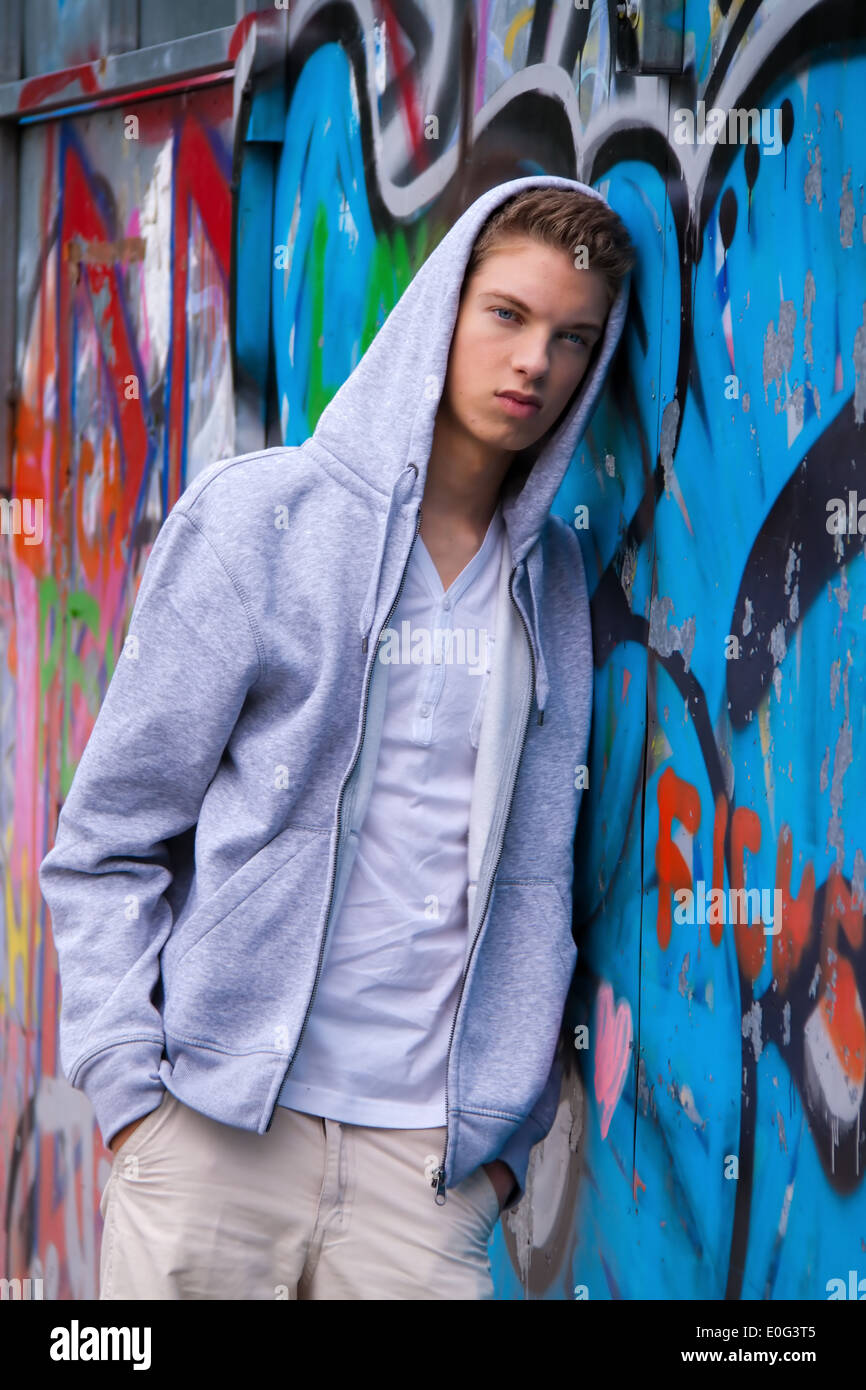 A cool looking youthful man before graffiti, Ein cool blickender Jugendlicher Mann vor Graffiti Stock Photo