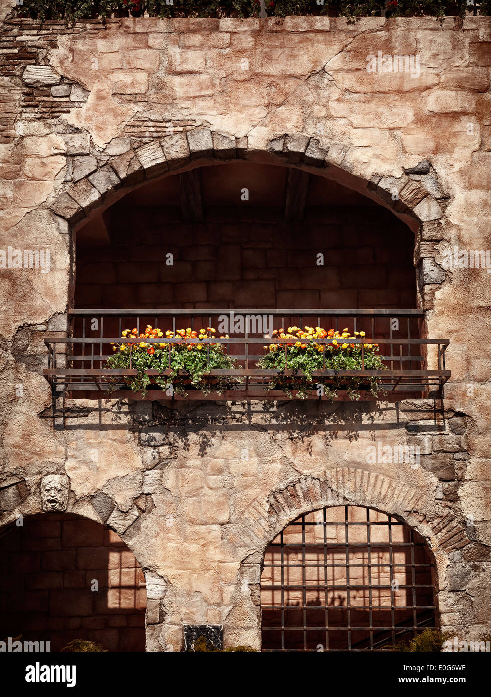 Wall of an old rustic house with flowers under a balcony, antique architecture in Venetian style Stock Photo