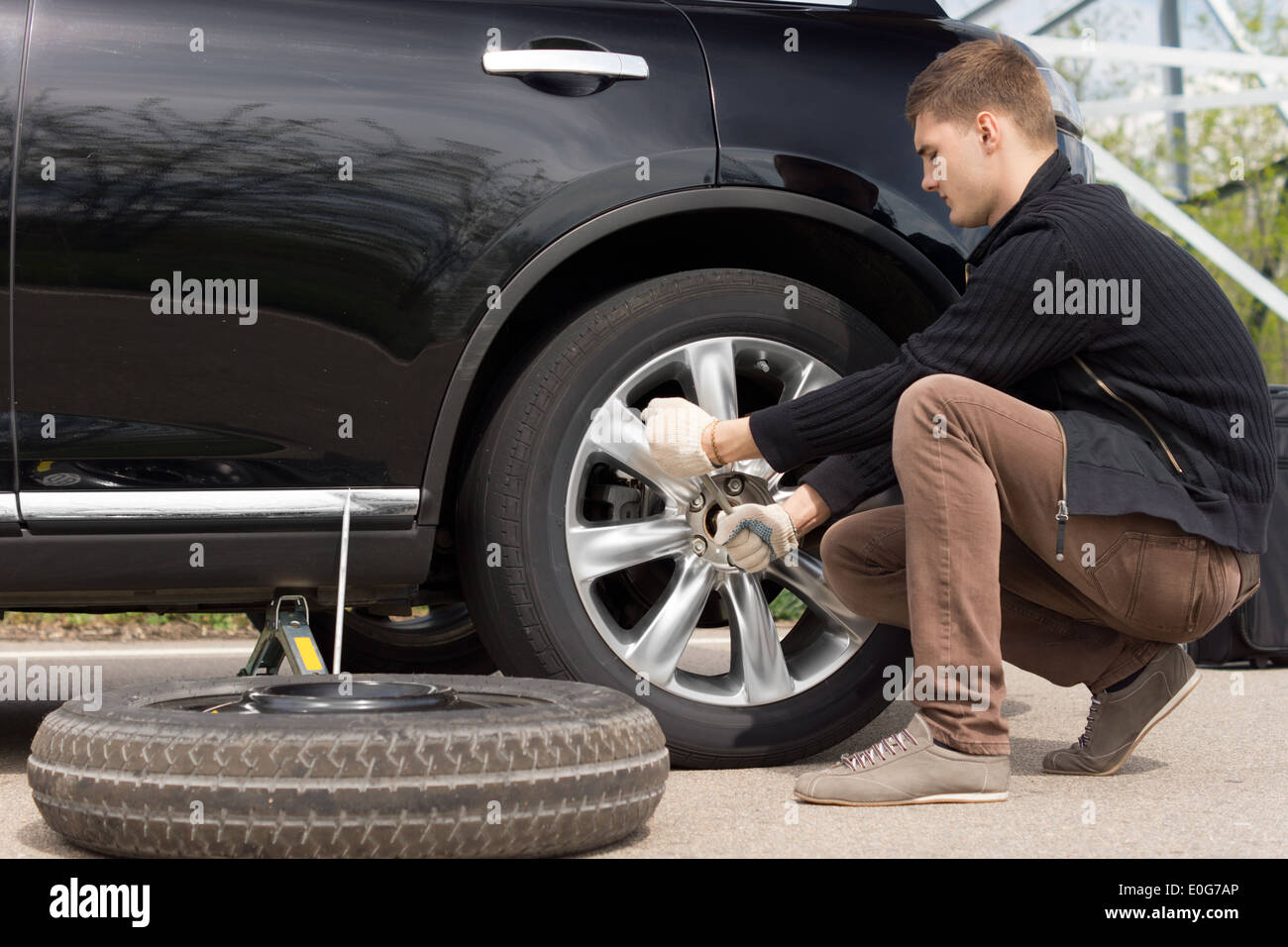 Mechanic changing a wheel during a roadside assistance call out to assist a driver in an