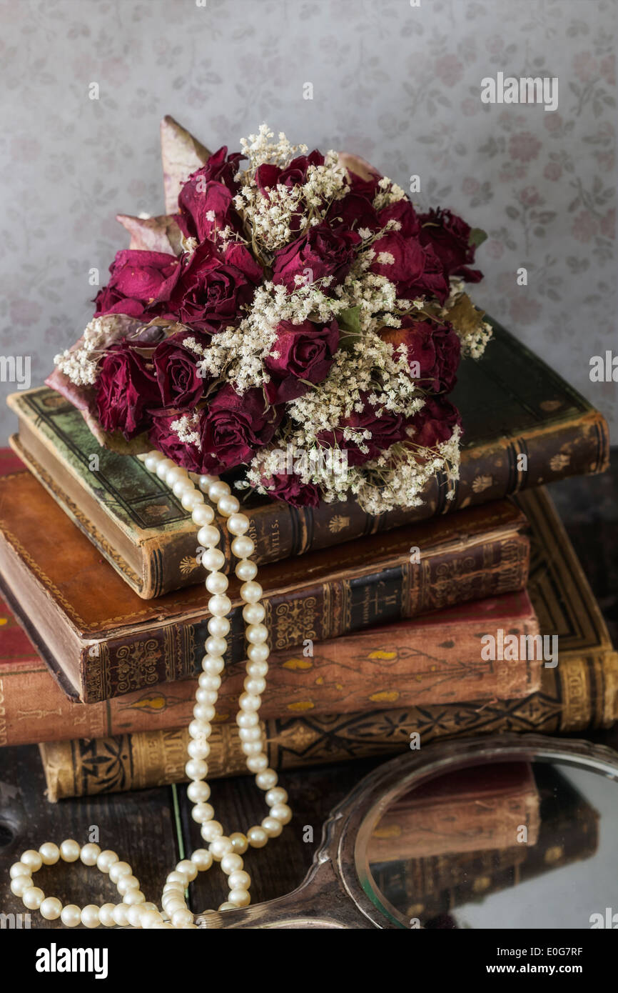 a dried rose bouquet on a pile of old books Stock Photo - Alamy