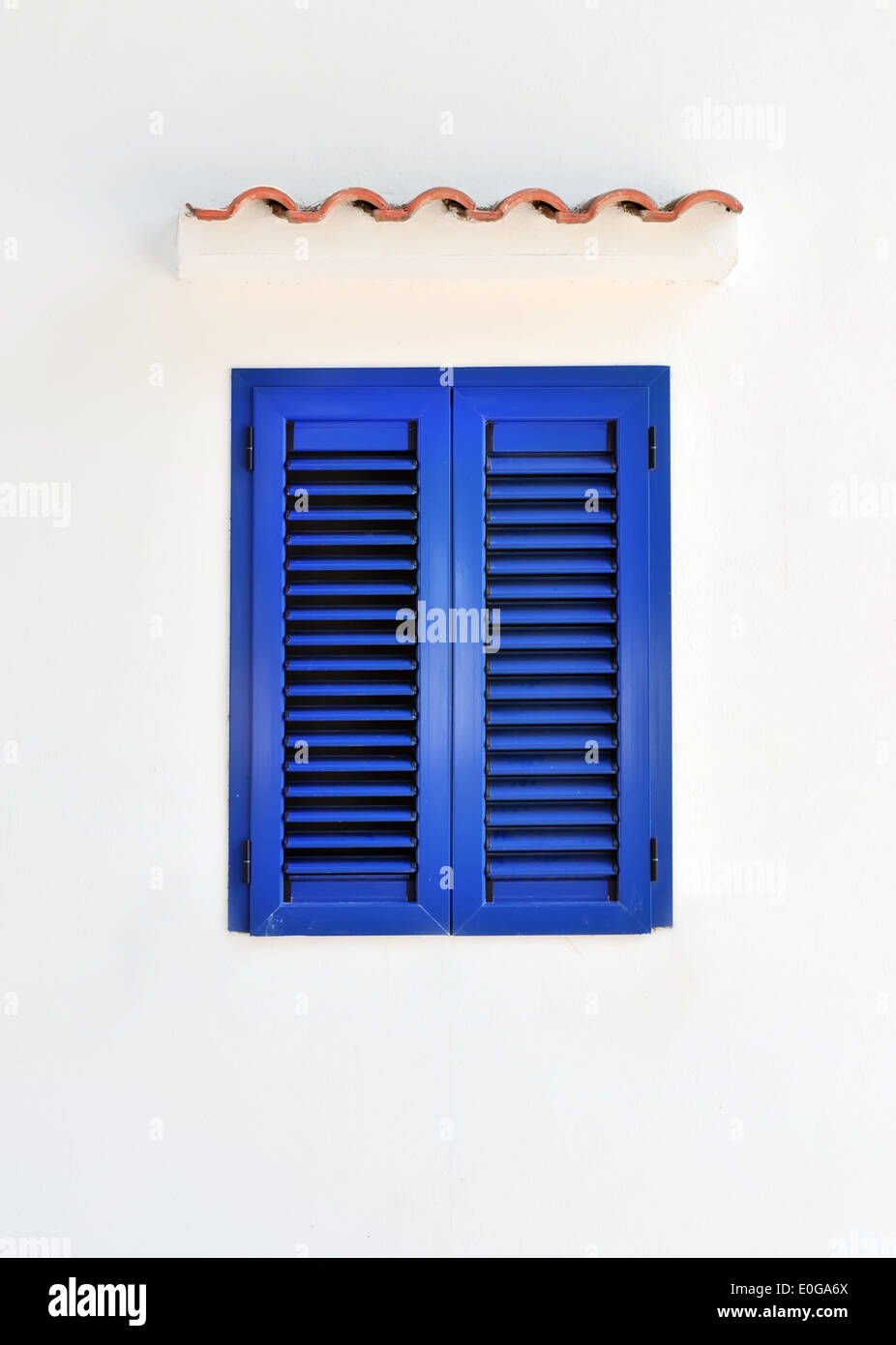 Closed window with blue shutters on white wall Stock Photo