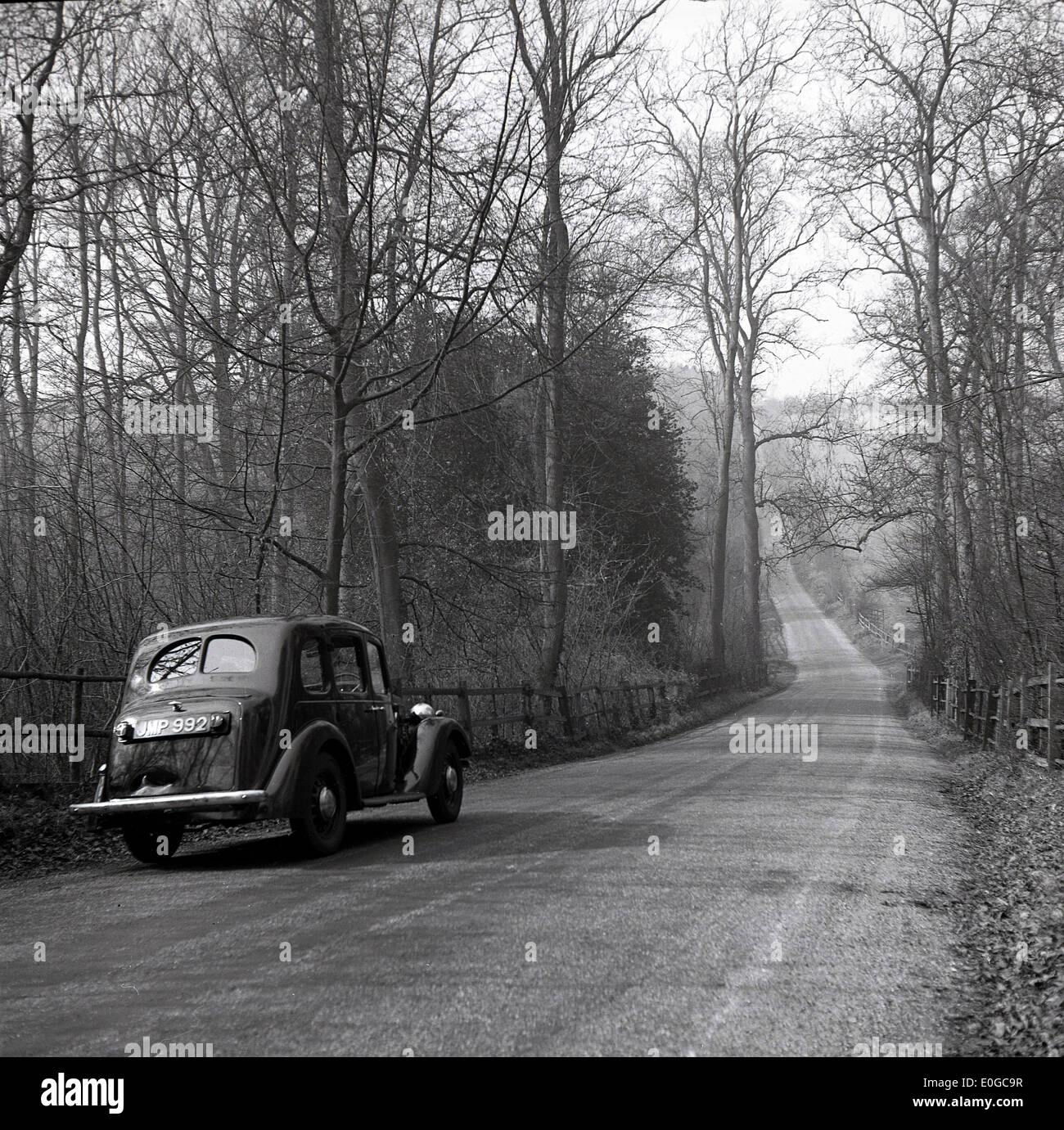 1950s and historical picture of a motor car of that era on a quiet tree lined country road, Stock Photo