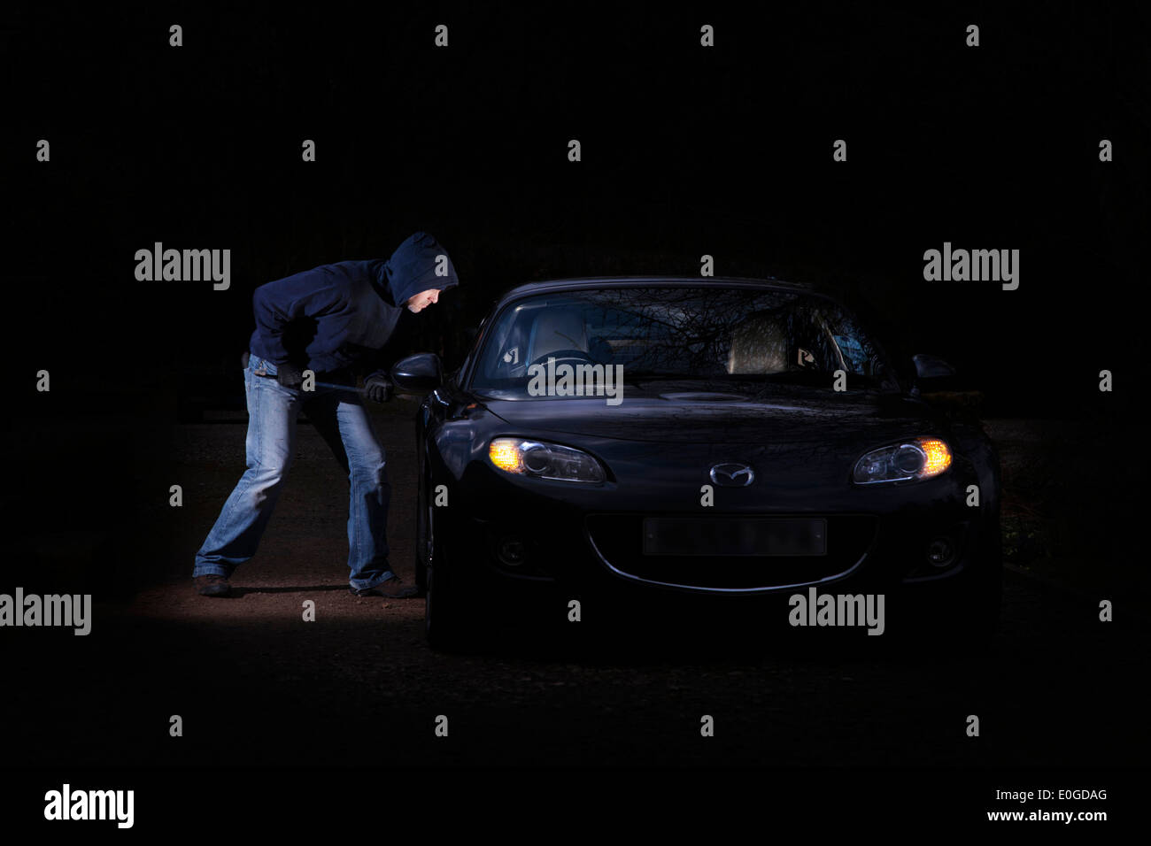 Thief breaking into parked a car at night. Stock Photo