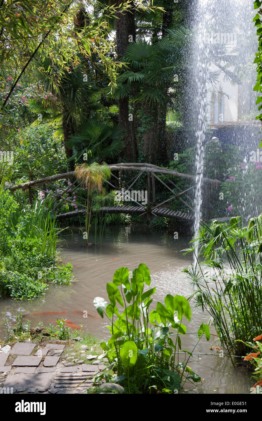 Bridge across a pond with fountain at Andre Hellers' Garden, Giardino Botanico, Gardone Riviera, Lake Garda, Lombardy, Italy, Eu Stock Photo