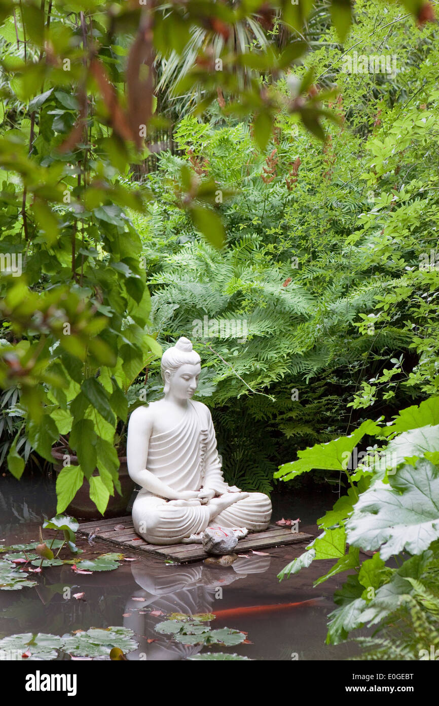 Buddha statue in a pond with water lilies and kois at Andre Hellers