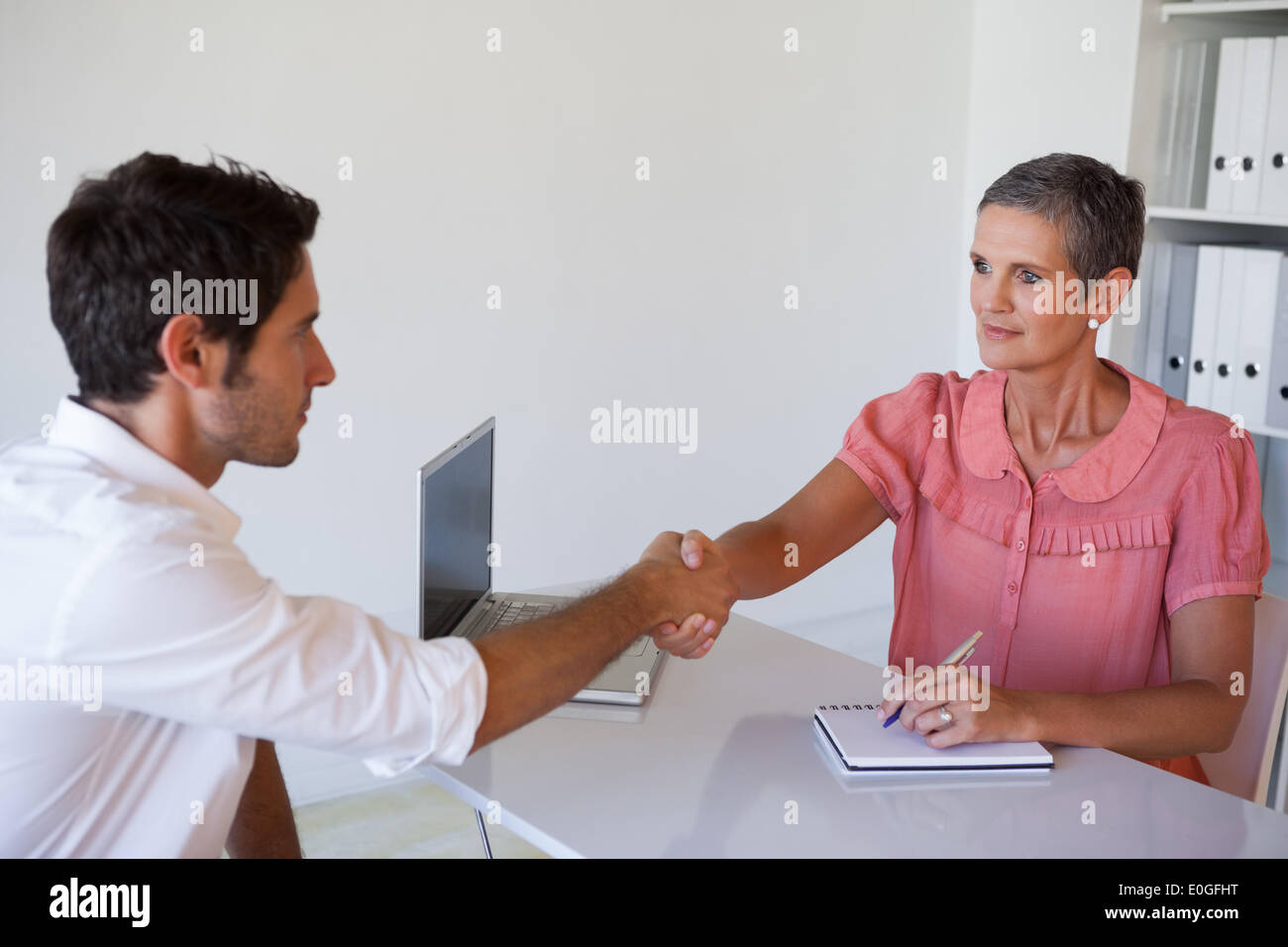 Casual business people shaking hands at desk Stock Photo Alamy