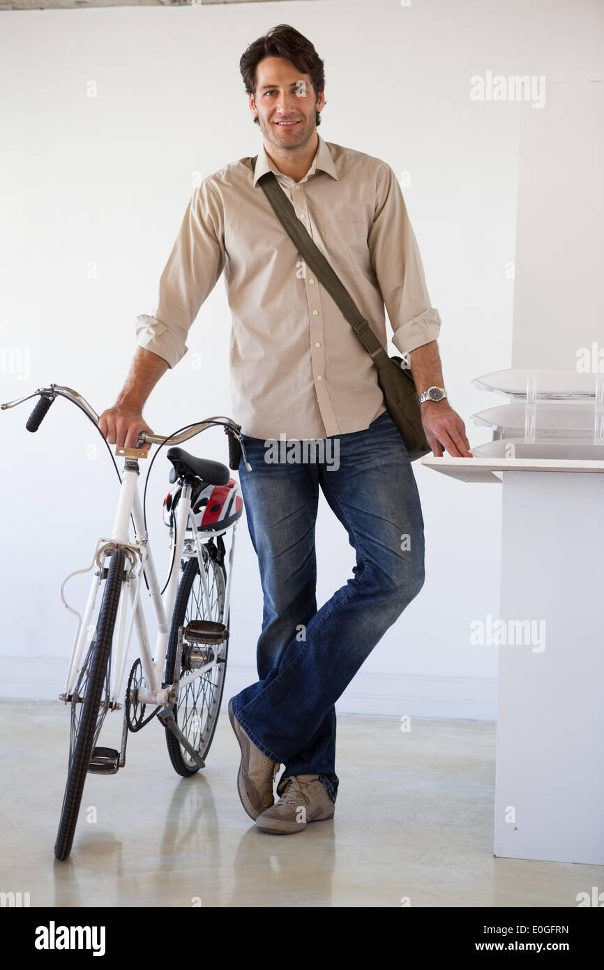 Casual businessman standing with his bike smiling at camera Stock Photo ...