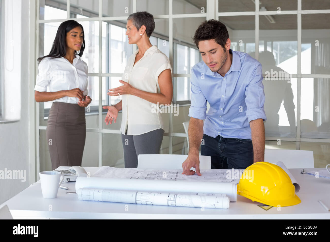 Workers talking and looking over plans Stock Photo