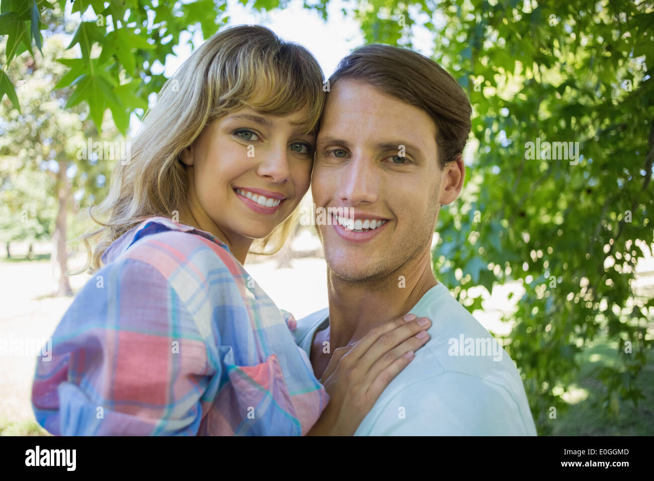 Cute couple smiling at camera and hugging in the park Stock Photo - Alamy