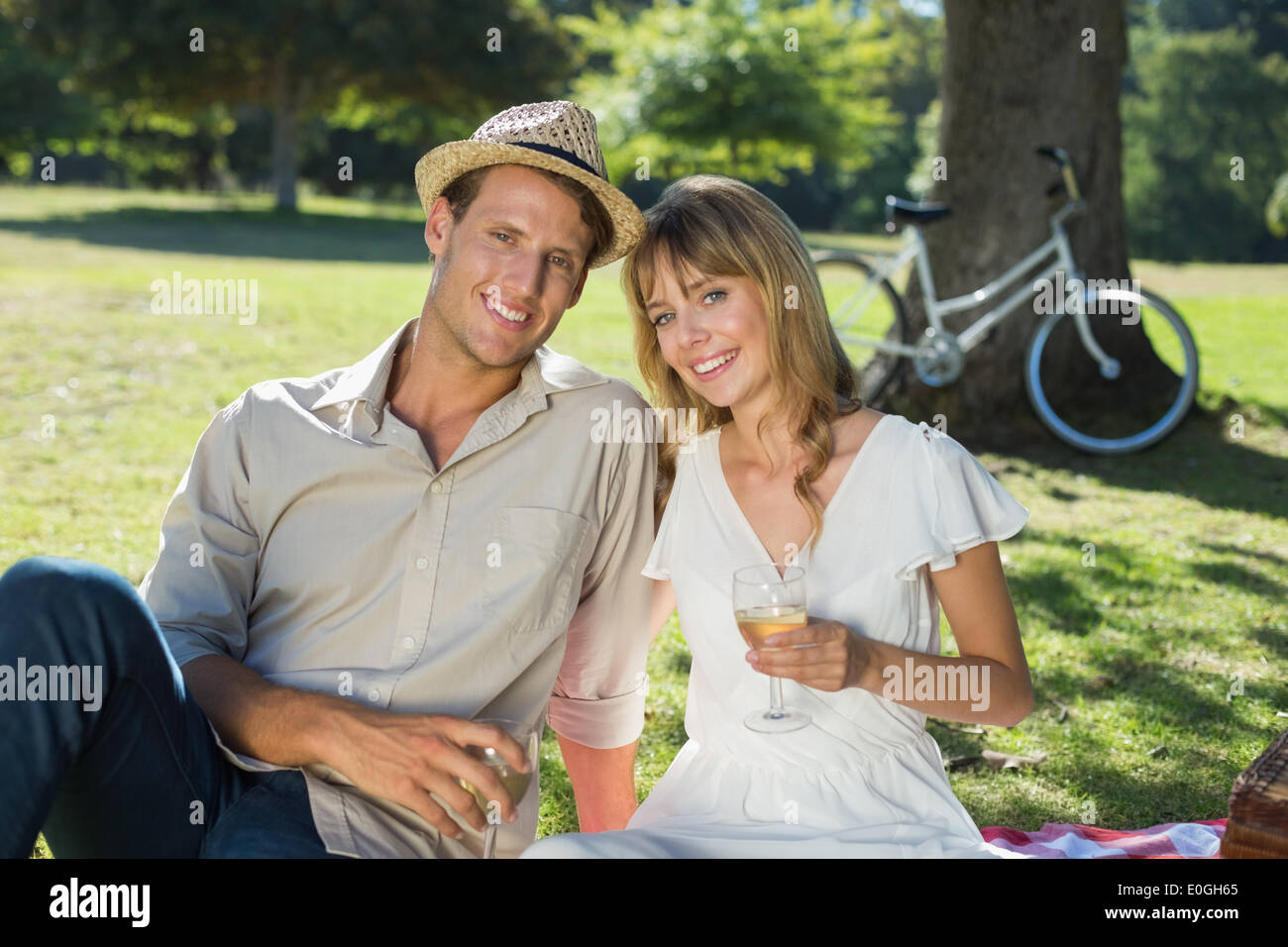 Cute couple drinking white wine on a picnic smiling at camera Stock ...