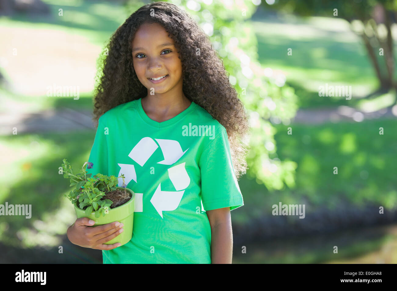 Young environmental activist smiling at the camera holding a potted plant Stock Photo