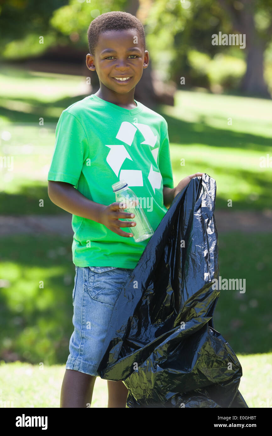 Young boy in recycling tshirt picking up trash Stock Photo